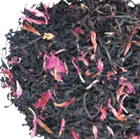 a pile of black tea with pink petals on top