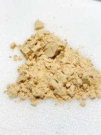 a pile of yellow powder on a white surface