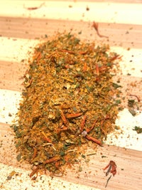 a pile of herbs and spices on a wooden cutting board