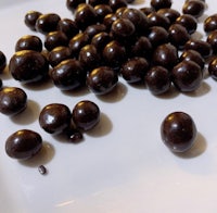 a plate of chocolate covered peanuts on a white plate