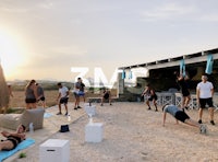 a group of people doing push ups on the beach