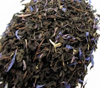 a pile of black tea with purple flowers on top