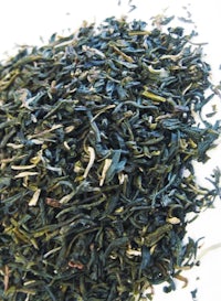 a pile of green tea on a white surface