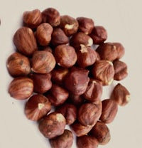 a pile of hazelnuts on a white surface