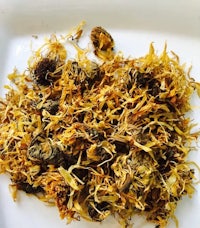 a pile of dried chamomile flowers on a white plate