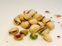 a pile of pistachios on a white table