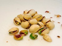 a pile of pistachios on a white table