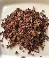 a pile of dried rose petals on a white plate