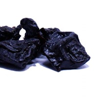 a pile of dried black grapes on a white background
